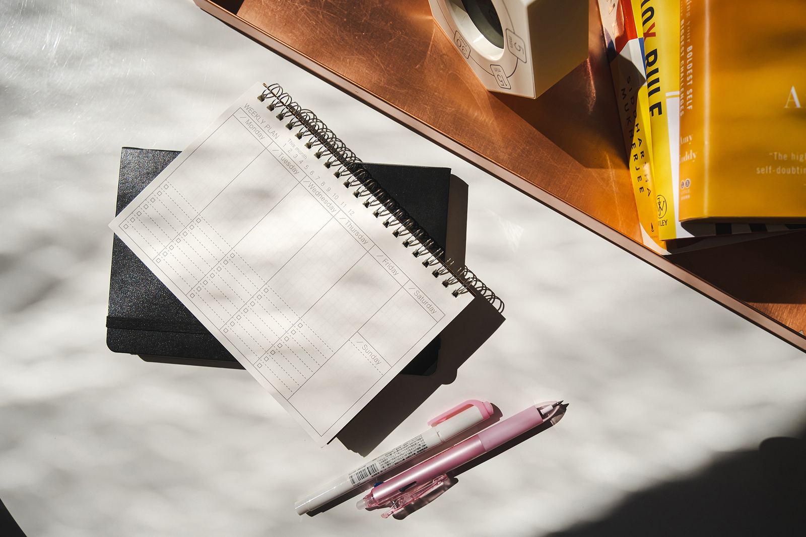 A weekly plan notebook on a sunlit desk
